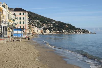 Scenic view of beach by buildings against sky