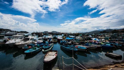 Boats moored at harbor against sky