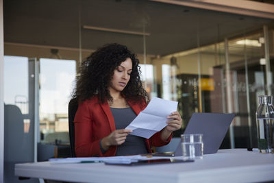 Businesswoman reading paper document at workplace