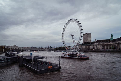 Ferris wheel in city against cloudy sky