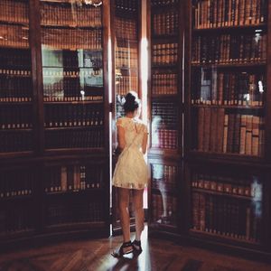 Woman standing against bookshelf in library