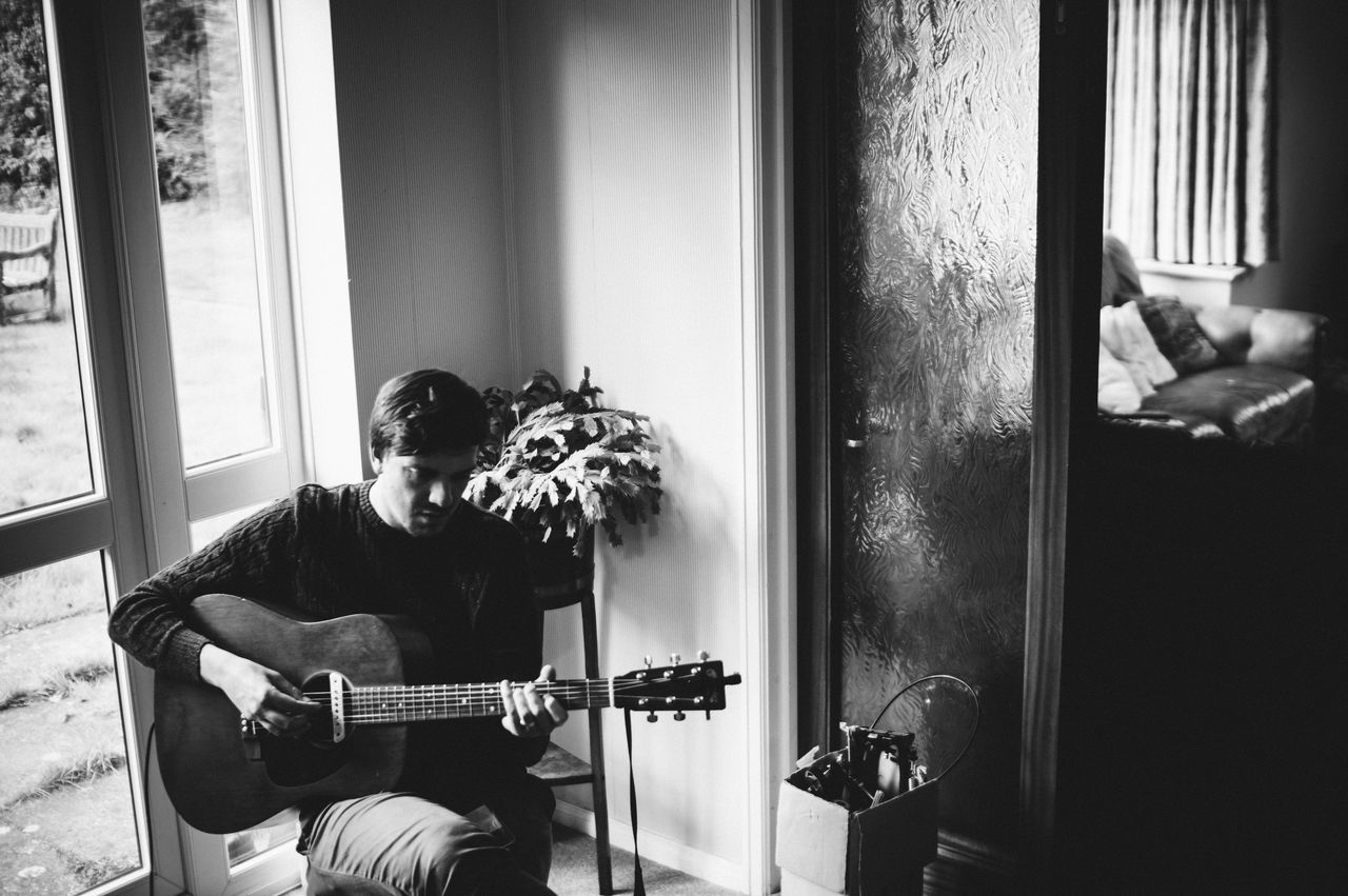 music, window, sitting, indoors, men, arts culture and entertainment, home interior, one person, guitar, musical instrument, plucking an instrument, only men, one man only, adults only, people, real people, adult, day, musician, young adult