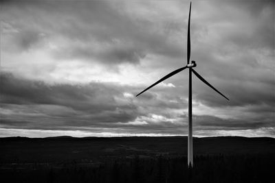 Low angle view of wind turbines on field against sky