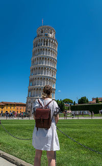 Rear view of woman on field against clear blue sky