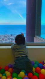 Rear view of woman looking at sea through window