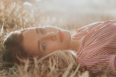 Portrait of young woman lying on field during sunset