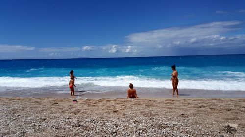 People at beach against sky on sunny day