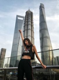 Woman pointing while standing against modern building