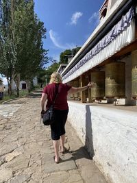 Rear view of woman walking on building against sky
