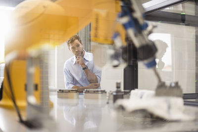 Businessman checking industrial robot in high tech company