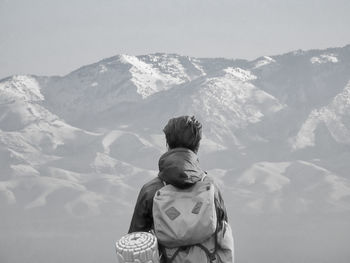 Rear view of man standing by mountain against sky