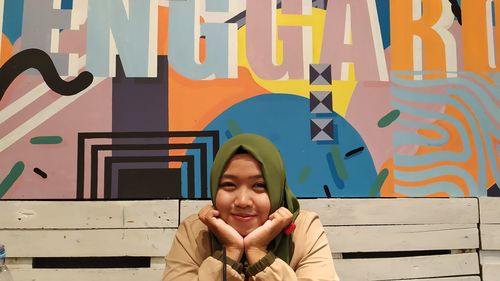 Portrait of smiling young woman against multi colored wall