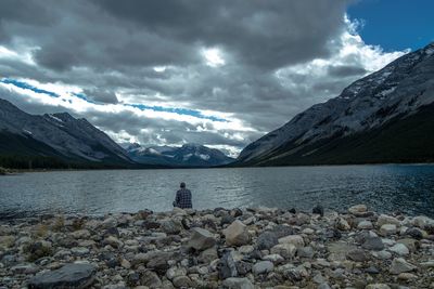 Rear view of snowcapped mountains by lake against sky