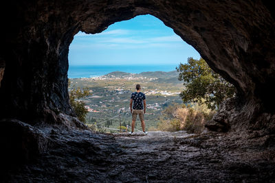 Rear view of man standing on rock by sea