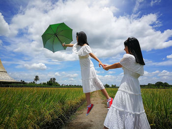 Girl pulling friend holding umbrella 