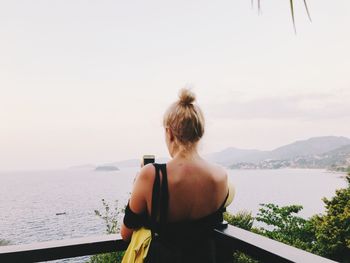 Rear view of woman photographing sea against clear sky