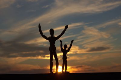 Silhouette men standing against sky during sunset