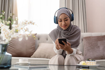 Young woman using phone while sitting at home