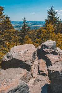 Stone wall by rocks against sky