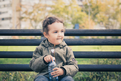 Cute girl looking away while holding water bottle at park