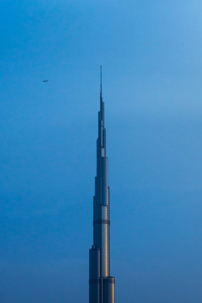 architecture, building exterior, sky, built structure, blue, low angle view, no people, nature, industry, tall - high, day, tower, outdoors, clear sky, copy space, building, factory, flying, bird, fuel and power generation, skyscraper, spire