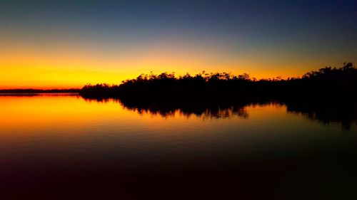 Scenic view of lake against clear sky at sunset