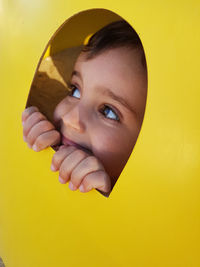 Close-up of smiling cute boy looking through play equipment