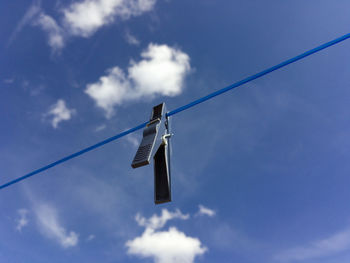 Low angle view of clothespins on clothesline against sky