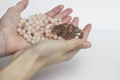 Close-up of hand holding hands over white background