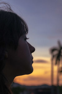 Woman looking away against sky during sunset