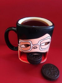 Close-up of coffee cup on table against red background