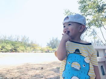 Cute boy looking away against sky