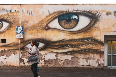 Portrait of young woman standing against graffiti wall