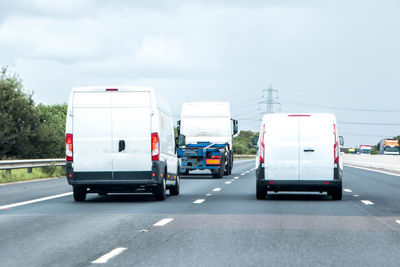 Vehicles on road against sky in city