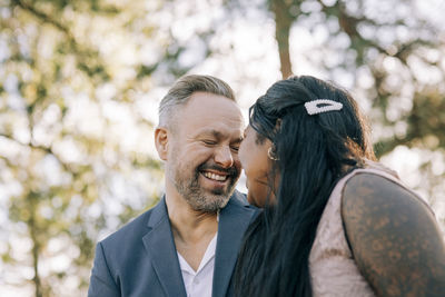 Cheerful mature groom squinting at young bride