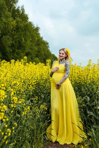 Woman standing by yellow flowers on field