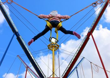 Low angle view of girl bungee jumping against sky