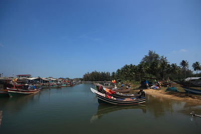 Boats moored in canal against clear blue sky