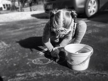 High angle view of girl drawing on street with chalk