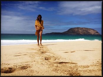 Rear view of man standing on beach against sky