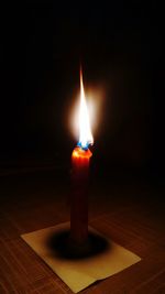 Close-up of lit candle in darkroom