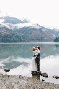 Woman standing by lake against mountains