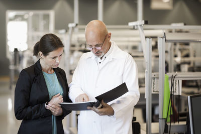 Male engineer and businesswoman looking at file in industry