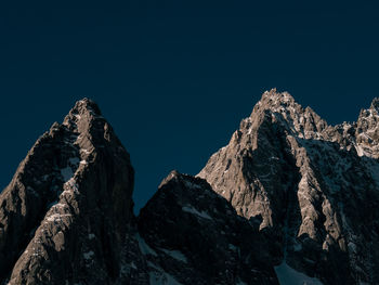 Low angle view of snowcapped mountains against clear sky