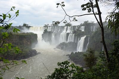 Scenic view of waterfall in forest against sky in foz do iguacu