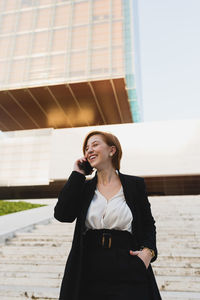 Smiling young woman standing against wall