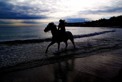 Silhouette man on beach against sky