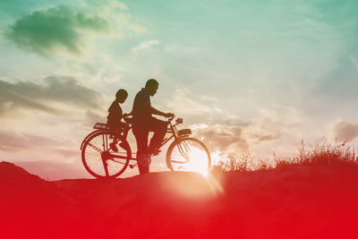 Silhouette man riding bicycle on field against sky