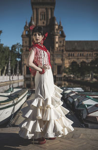 Young woman in traditional clothes standing by lake in city