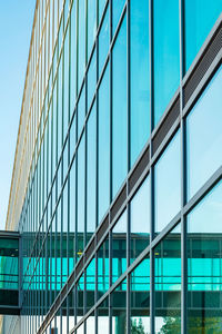 Low angle view of glass building against clear blue sky